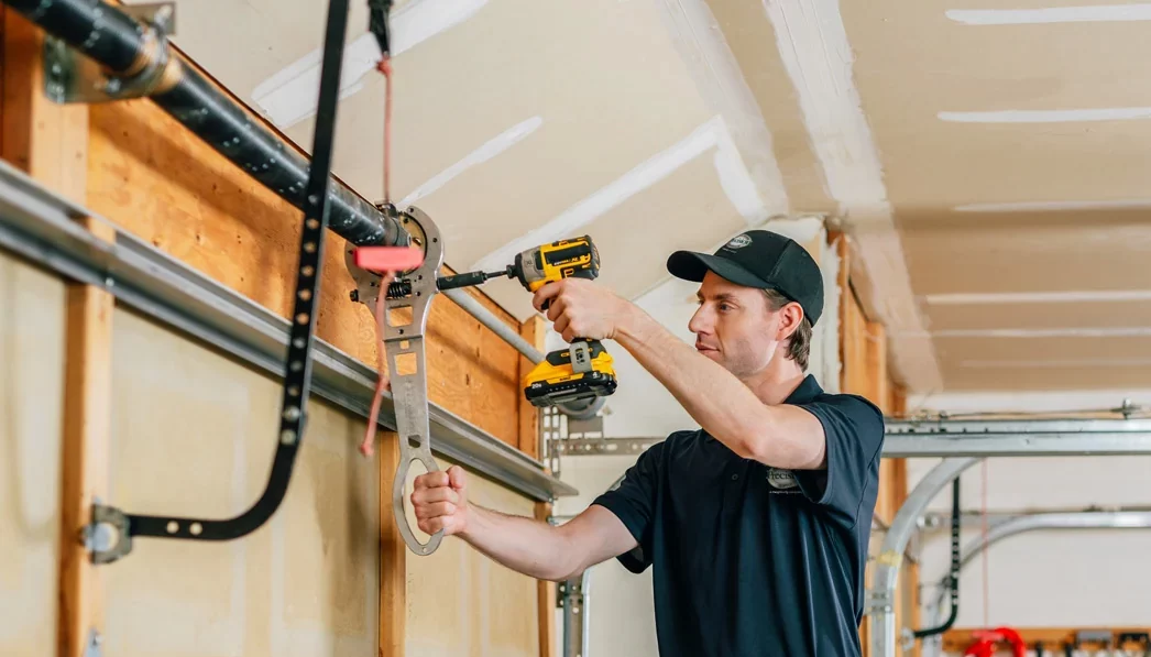 Precision Garage Door technician repairing a spring Technician repairing garage door rollers and track system.