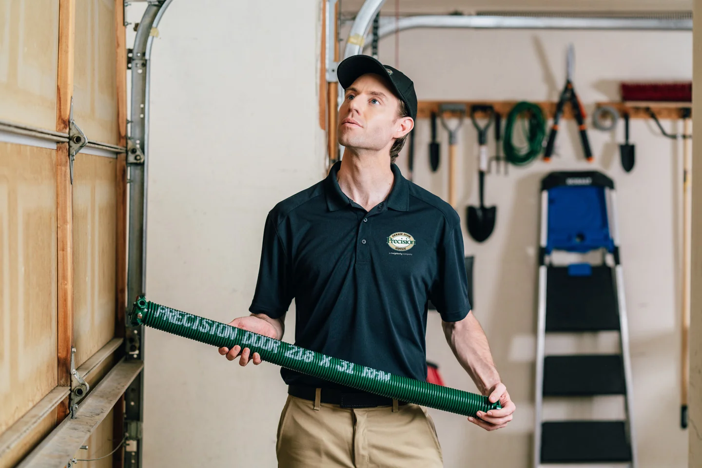 Precision Garage Door technician holding a garage door spring for repair and replacement.