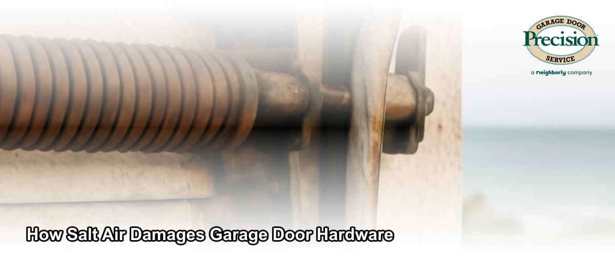 Corroded garage door spring and track hardware on a coastal Ventura County home with ocean visible in the background