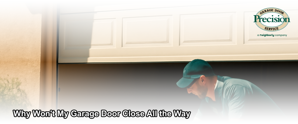 A residential garage door stopped partially open in Ventura California with a technician inspecting the track and sensors
